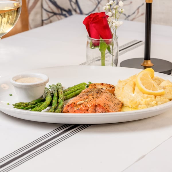 Grilled salmon with asparagus, mashed potatoes, and a lemon wedge on a white plate at Water Street Grill.