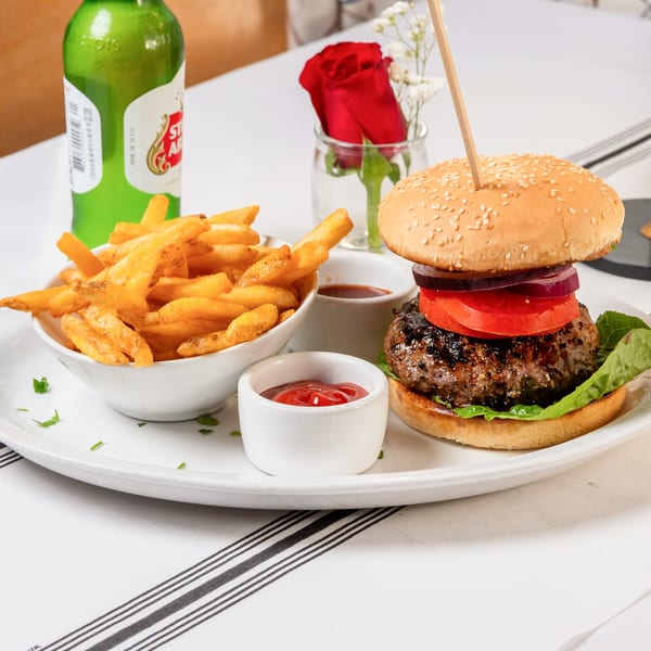 A Water Street Grill burger with fries, ketchup, and a beer bottle on a white tablecloth.