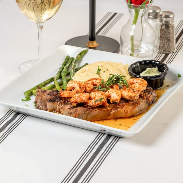 Water Street Grill's steak and shrimp entree with mashed potatoes and asparagus, served with white wine.