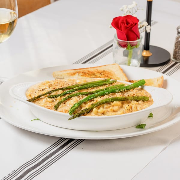 Creamy macaroni and cheese topped with asparagus and breadcrumbs, served with toast and wine.